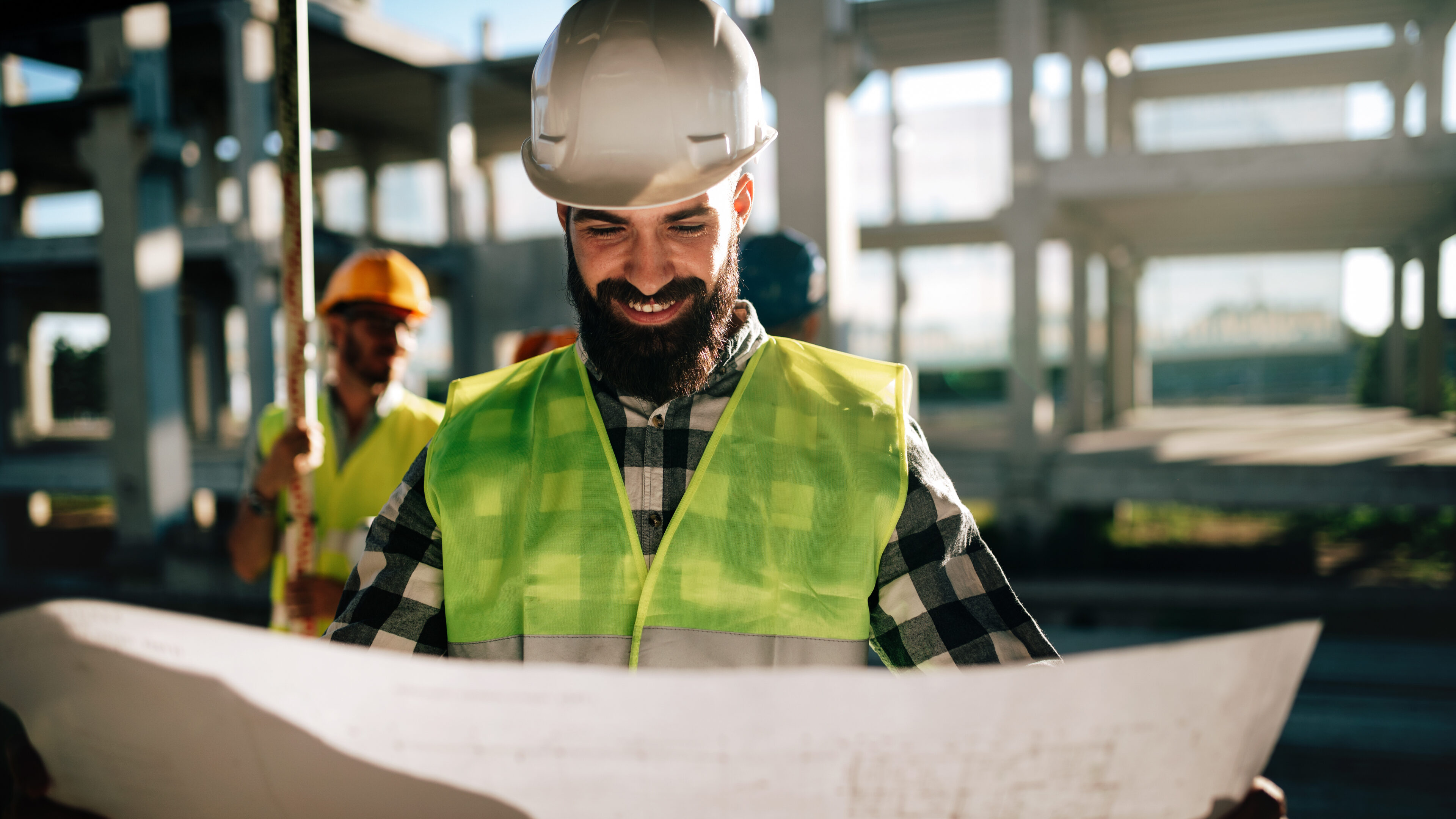 Zufriedener Ingenieur, der auf einer Baustelle zufrieden auf seine Planmessungen schaut