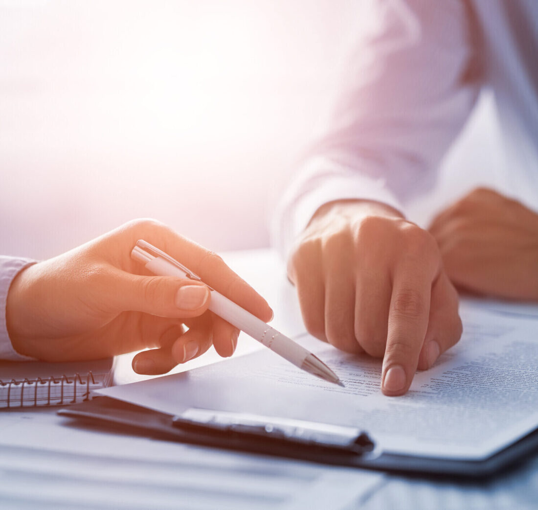 Zwei Personen besprechen im Rahmen eines Recruiting‑Prozesses ein Dokument, wobei eine Hand auf eine Textstelle zeigt und die andere einen Stift hält.