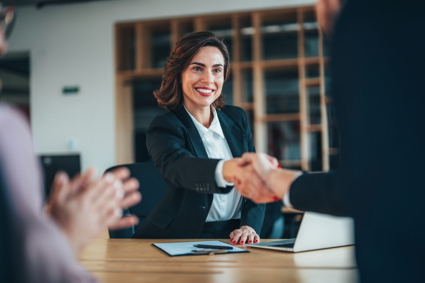 Group of three happy people handshake after signing a contract in the office
