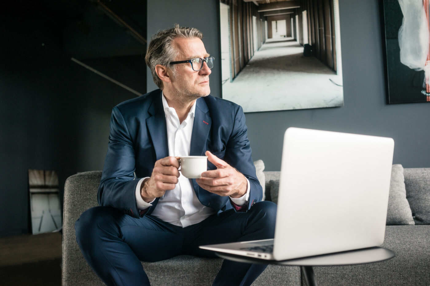 Älterer Geschäftsmann sitzt mit einer Tasse Kaffee auf der Couch