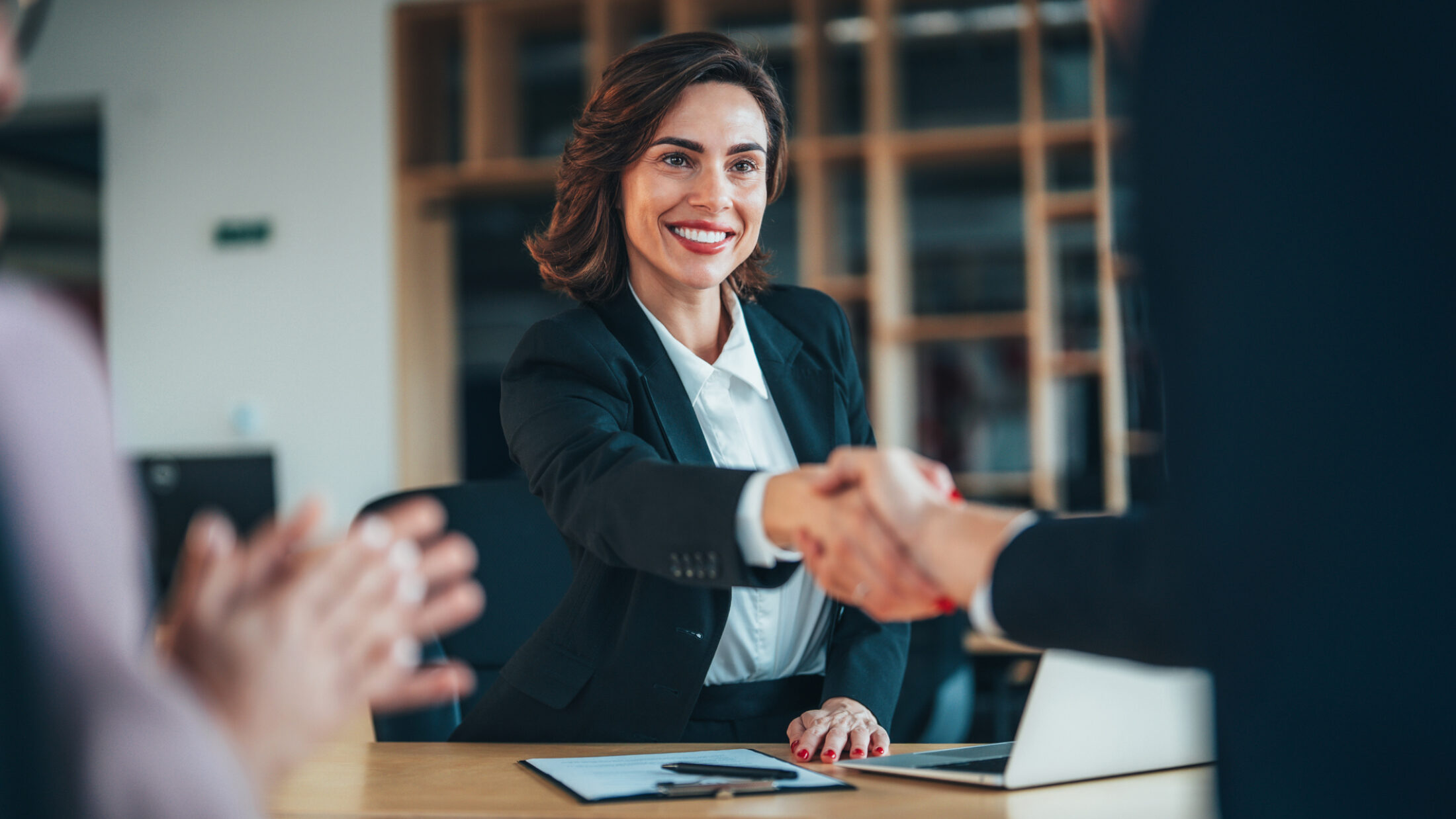 Group of three happy people handshake after signing a contract in the office