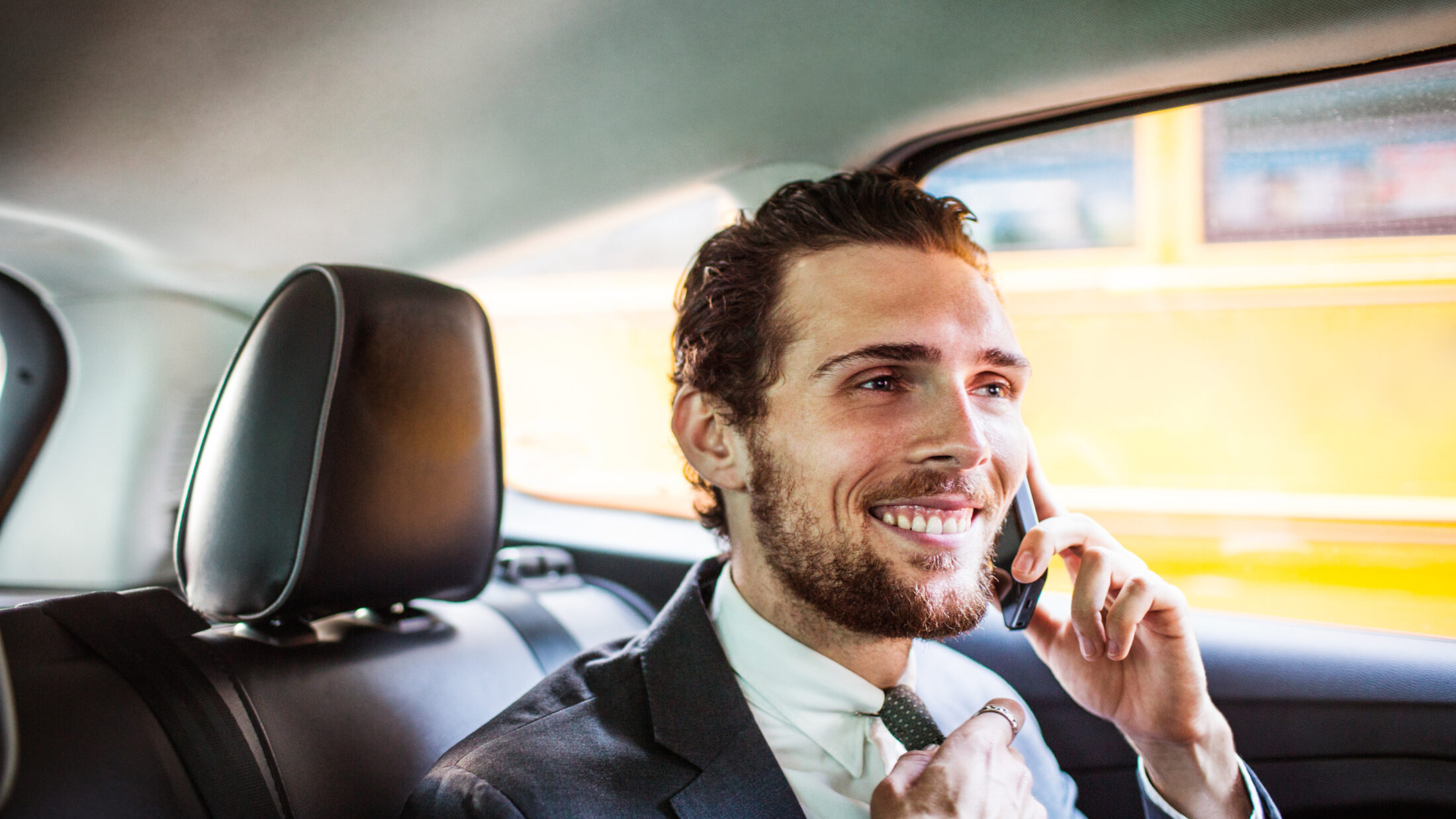 Lächelnder Geschäftsmann telefoniert, während er im Auto sitzt