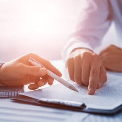 Zwei Personen besprechen im Rahmen eines Recruiting‑Prozesses ein Dokument, wobei eine Hand auf eine Textstelle zeigt und die andere einen Stift hält.