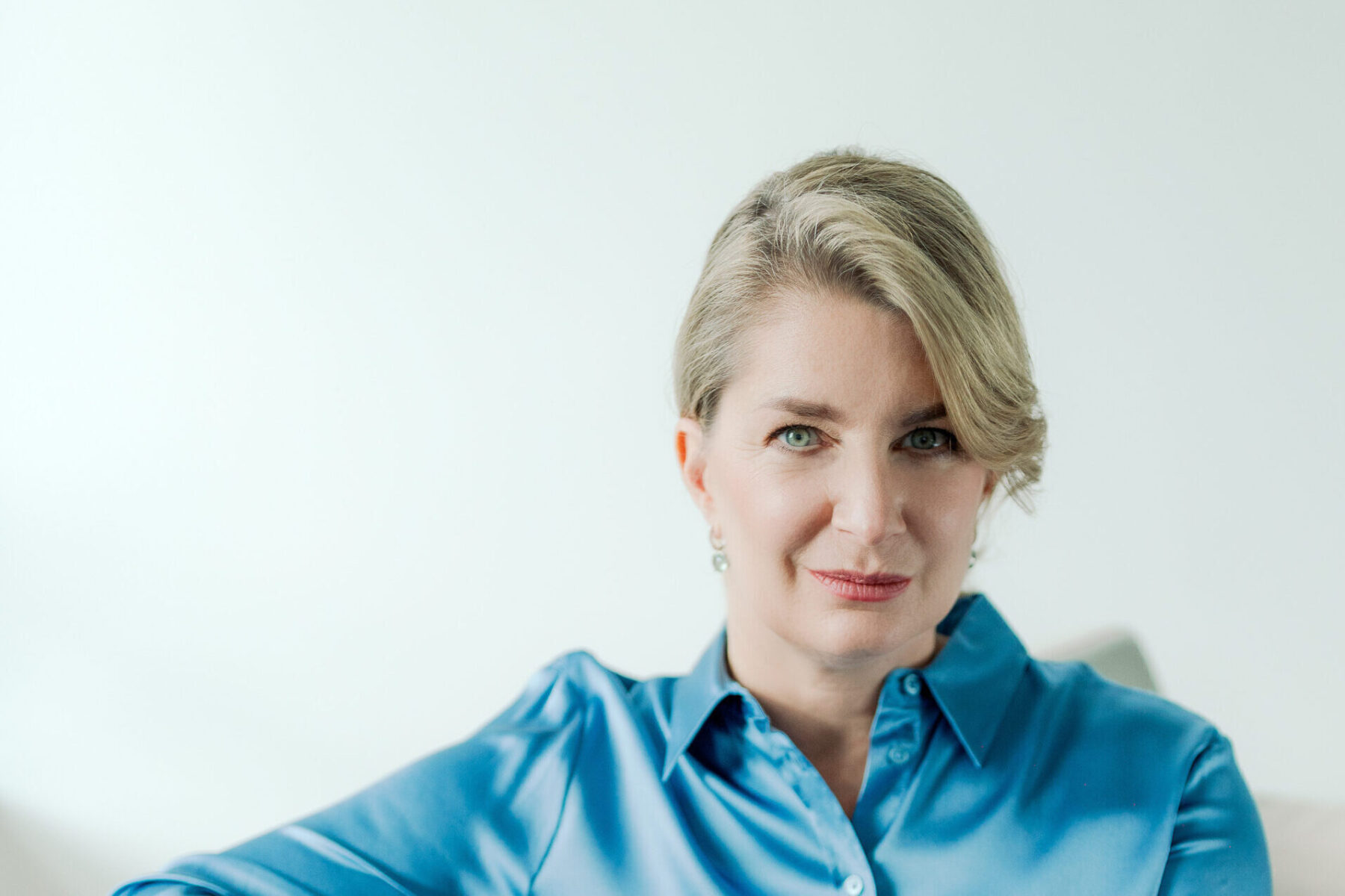 Frau sitzt auf einem Sofa und blickt in die Kamera